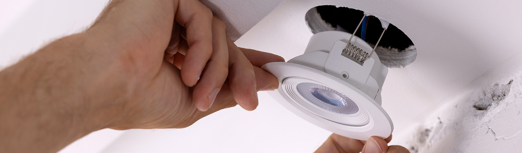 een installateur plaatst een inbouwspot in een plafond