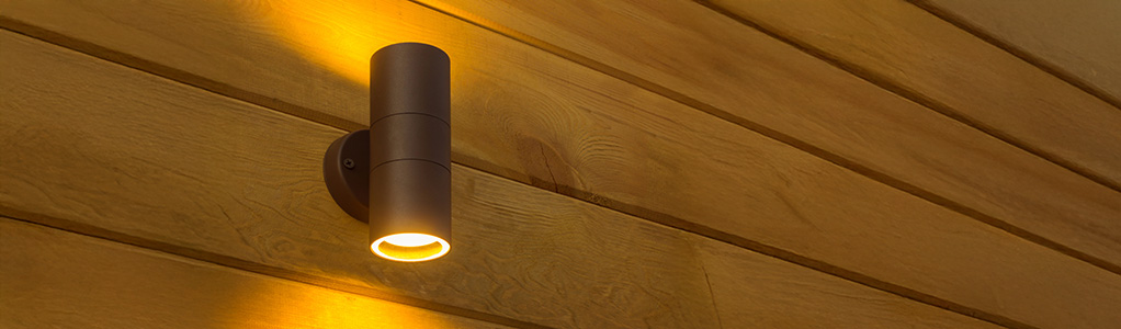 Een wandlamp voor buiten, gemonteerd op een schutting.
